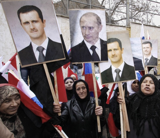FILE - In this Sunday, March 4, 2012 file photo, Syrians hold posters of Syrian President Bashar Assad, far left, and Russian President Vladimir Putin, second left, during a pro-Syrian goverment protest in front of the Russian Embassy in Damascus, Syria. In ramping up its military involvement in Syria's civil war, Russia appears to be betting that the West, horrified by Islamic State's atrocities, may be willing to tolerate Assad for a while, perhaps as part of a transition. (AP Photo/Muzaffar Salman, File)